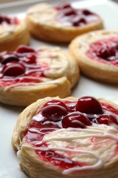 several cookies with cream and cherries on them