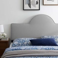 a bed with a blue headboard and two pictures on the wall above it