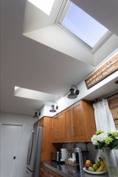 a kitchen with wooden cabinets and a skylight above the counter top, along with a bowl of fruit