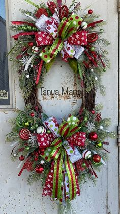 a christmas wreath hanging on the front door of a house with red, green and white decorations