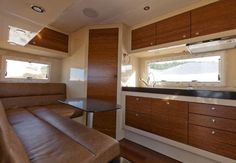 the interior of an rv with wood cabinets and leather couches in front of it