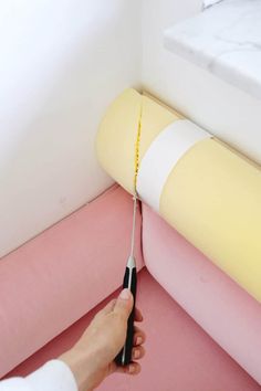 a person is using a pair of scissors to cut fabric on the edge of a bed