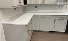 an empty kitchen with white cabinets and drawers