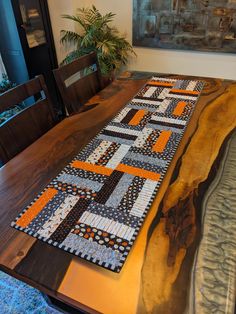 the table is made from wood and has an orange patchwork design on it's edge