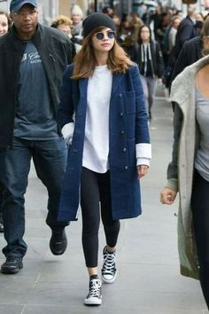 a man and woman walking down the street in front of some people wearing black sneakers