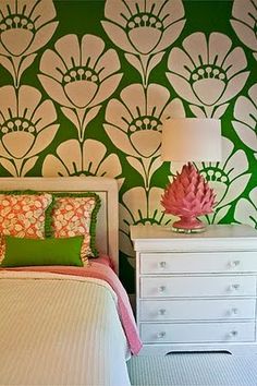 a white bed sitting next to a green wallpaper covered in pink and white flowers