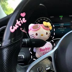 a hello kitty stuffed animal sitting in the driver's seat of a car