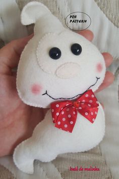 a hand holding a white stuffed animal with a red bow