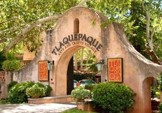 the entrance to an outdoor restaurant with trees and bushes