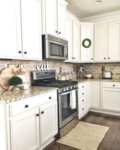 a kitchen with white cabinets and an oven in the center, surrounded by wood flooring