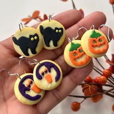 a hand holding four decorated halloween earrings