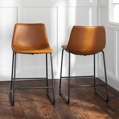 two brown chairs sitting on top of a wooden floor