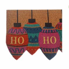 three colorful christmas ornaments hanging from hooks on a door mat with the word ho written in gold