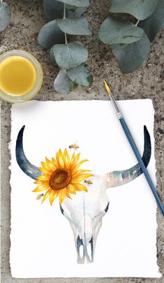 a painting of a bull skull with a sunflower on it's head next to a paintbrush