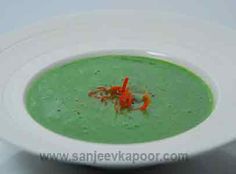 a white bowl filled with green soup and garnished with red fish on top