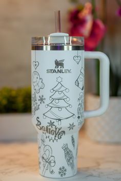 a white travel mug with christmas designs on the front and side, sitting on a table