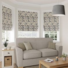 a living room filled with furniture and windows covered in roman blind shades on top of them