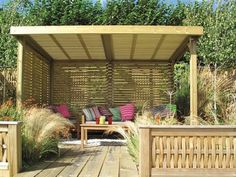 a wooden bench sitting under a pergolated covered area with purple and green pillows