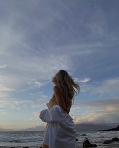 a woman standing on top of a beach next to the ocean