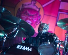 a man in cat mask playing drums on stage