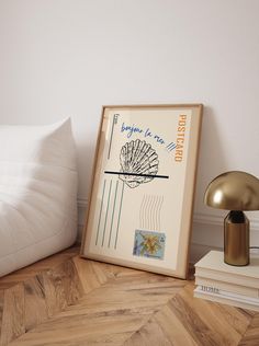 a framed poster sitting on top of a wooden floor next to a lamp and pillows