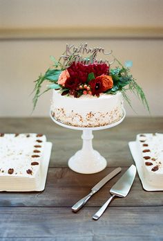 a white cake sitting on top of a wooden table next to two plates with silverware