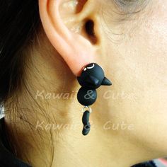 a close up of a person's ear wearing black cat earrings