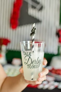 a person holding up a shot glass with the words talk derby to me on it