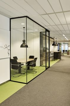 an office with glass walls and green carpeted flooring is shown in this image