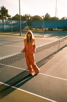 a woman standing on a tennis court holding a racquet and posing for the camera