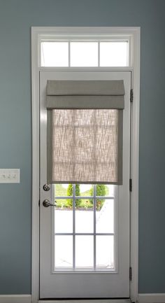 a white door with a window and blinds on the top half, in front of a blue wall