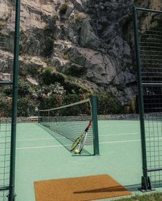 there is a tennis court with a net on the ground and mountains in the background