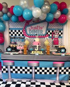 a table with balloons, cake and desserts on it in front of a checkered wall