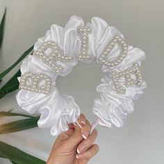 the bride's wedding ring pillow is being held up by her hand and decorated with pearls