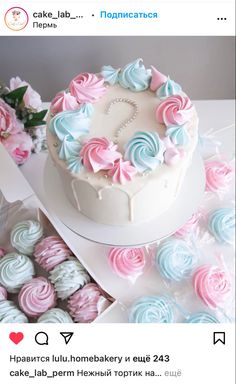 a white cake sitting on top of a table covered in pink and blue frosting