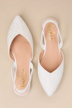 a pair of white wedding shoes with gold lettering on the toe and heel, against a beige background