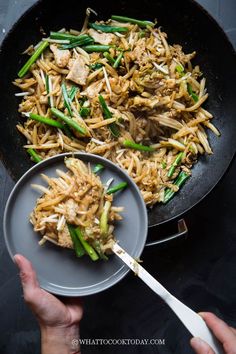 someone is holding a pan with stir fry and green beans in it while another person holds a spatula over the skillet