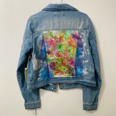 a blue jean jacket with an abstract painting on it