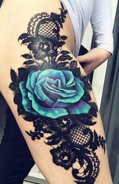 a woman's thigh with a blue rose tattoo on the side and black lace around it