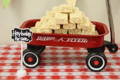 a red wagon filled with rice krispy treats on top of a checkered table cloth