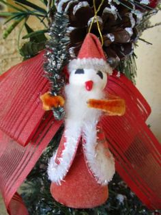 a christmas ornament hanging from the side of a tree with pine cones on it