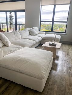 a large white couch sitting in front of a window on top of a hard wood floor