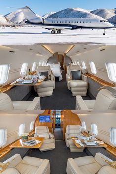 the inside of an airplane with tables and couches in front of snow covered mountains