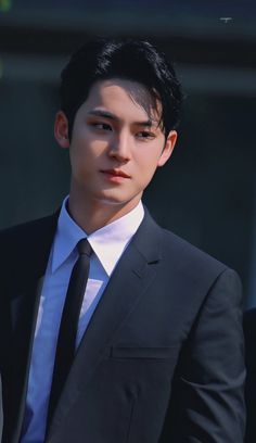 a young man in a suit and tie looking at the camera with serious expression on his face