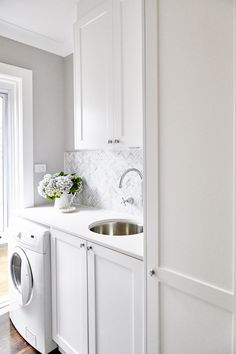 a laundry room with white cabinets and wood floors