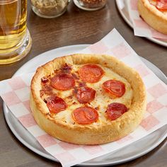 a pepperoni pizza sitting on top of a white plate next to a glass of beer