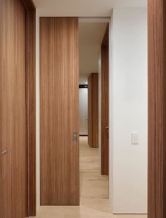 an empty hallway with wooden doors and white walls