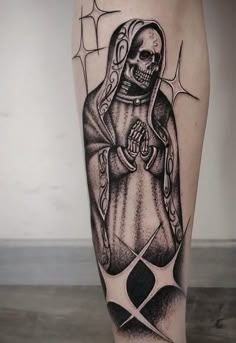 a black and white tattoo on the leg of a person with a skeleton holding a cross