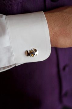 a man wearing a white shirt and cuff with a silver bat on it's lapel