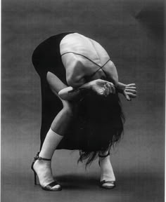 a black and white photo of a woman bending over with her legs bent in the air